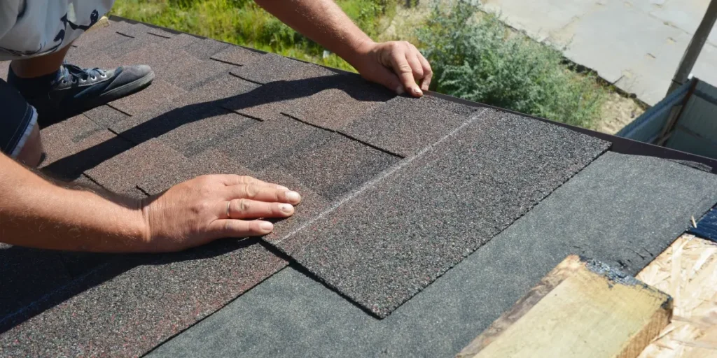Roofing professional inspecting and installing asphalt roof shingles to prevent roof leaks and maintain a durable residential roof