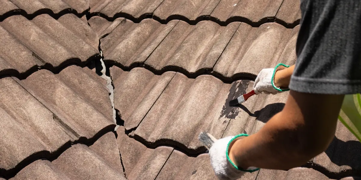 Cracked roof tiles being treated with a protective coating, highlighting the importance of repairing roof damage before roof painting in Sydney