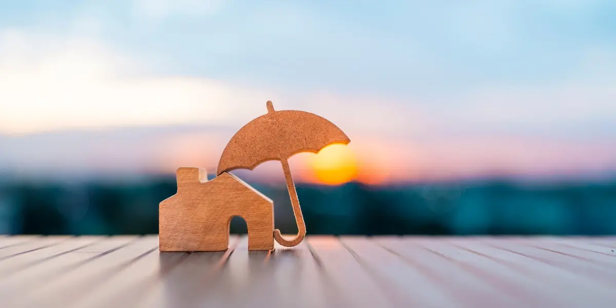 Wooden house model protected by an umbrella, symbolising the role of roof painting in protecting homes from weather damage in Sydney
