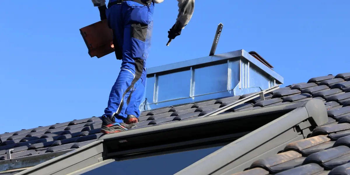 Professional roofer inspecting tiled roofing and chimney flashing as part of roof maintenance and protective roof coating services in Sydney