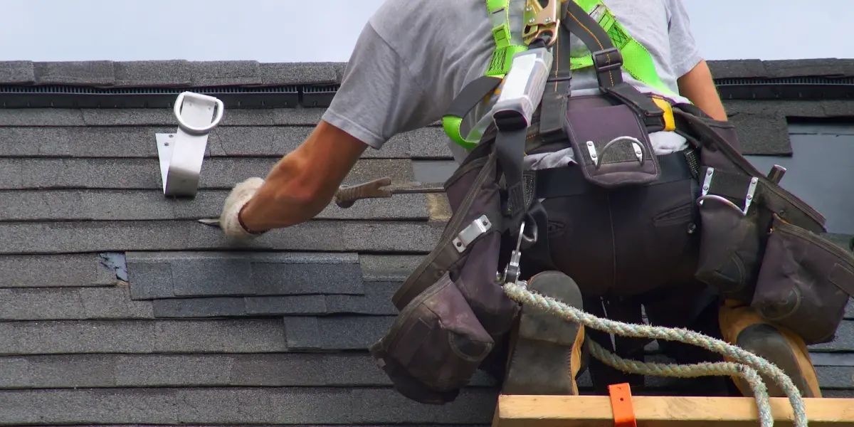 Professional roofer inspecting asphalt shingles before applying a protective roof coating to improve weather resistance and help prevent leaks