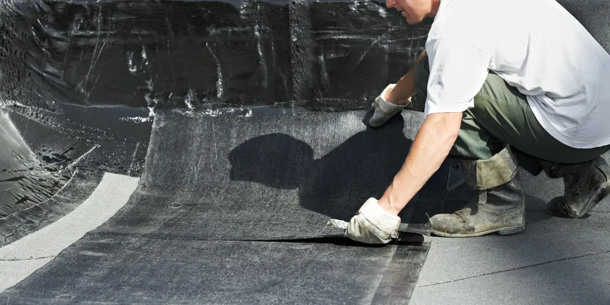 Professional roofer inspecting asphalt shingles before applying a protective roof coating to improve weather resistance and help prevent leaks