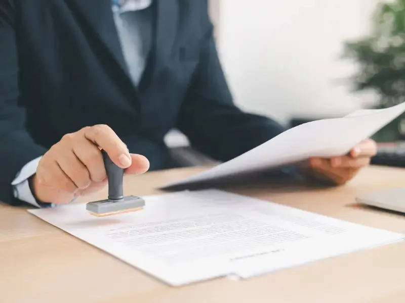 Professional reviewing and stamping roofing service paperwork on a desk