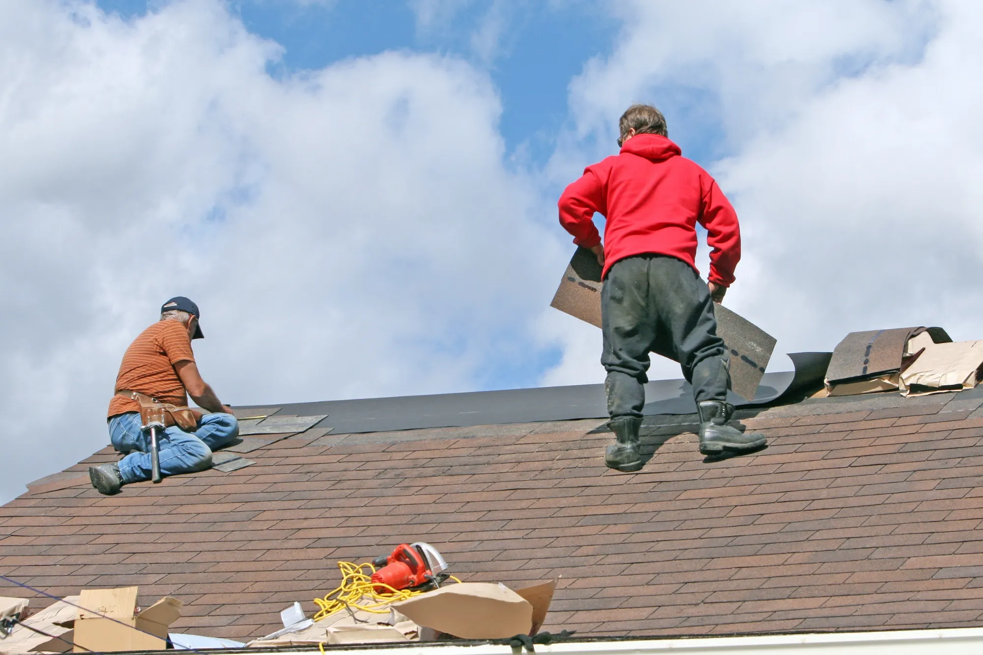 Roof restoration in Sydney – two roofers repairing and re-laying roofing on a house roof