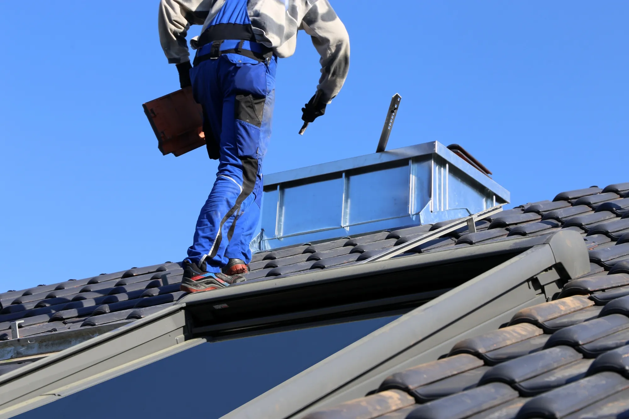Roofer inspecting a tiled roof before roof painting and restoration in Sydney