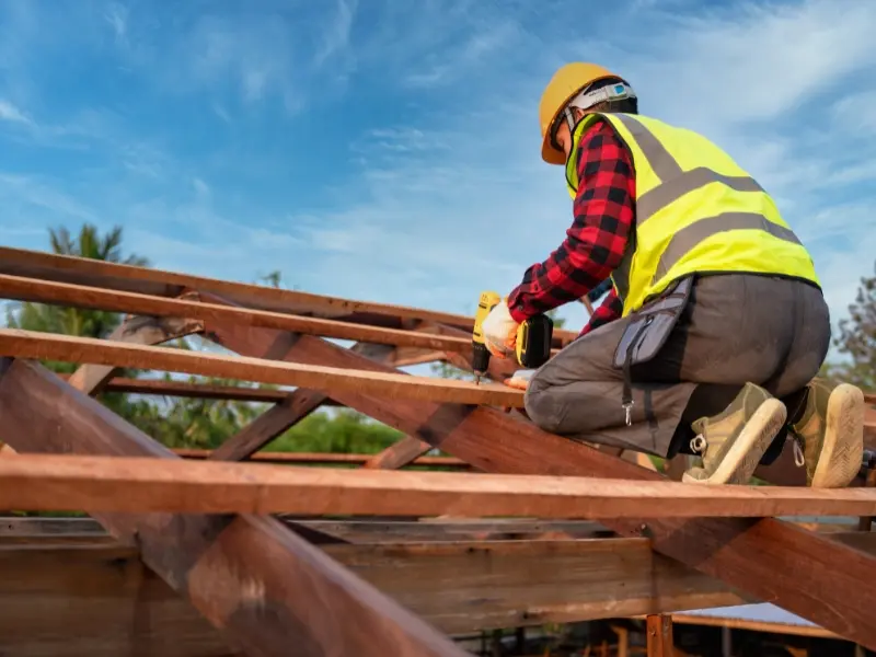 Roof Repairs 4 Roofer securing timber roof trusses with a power drill during residential roof framing construction
