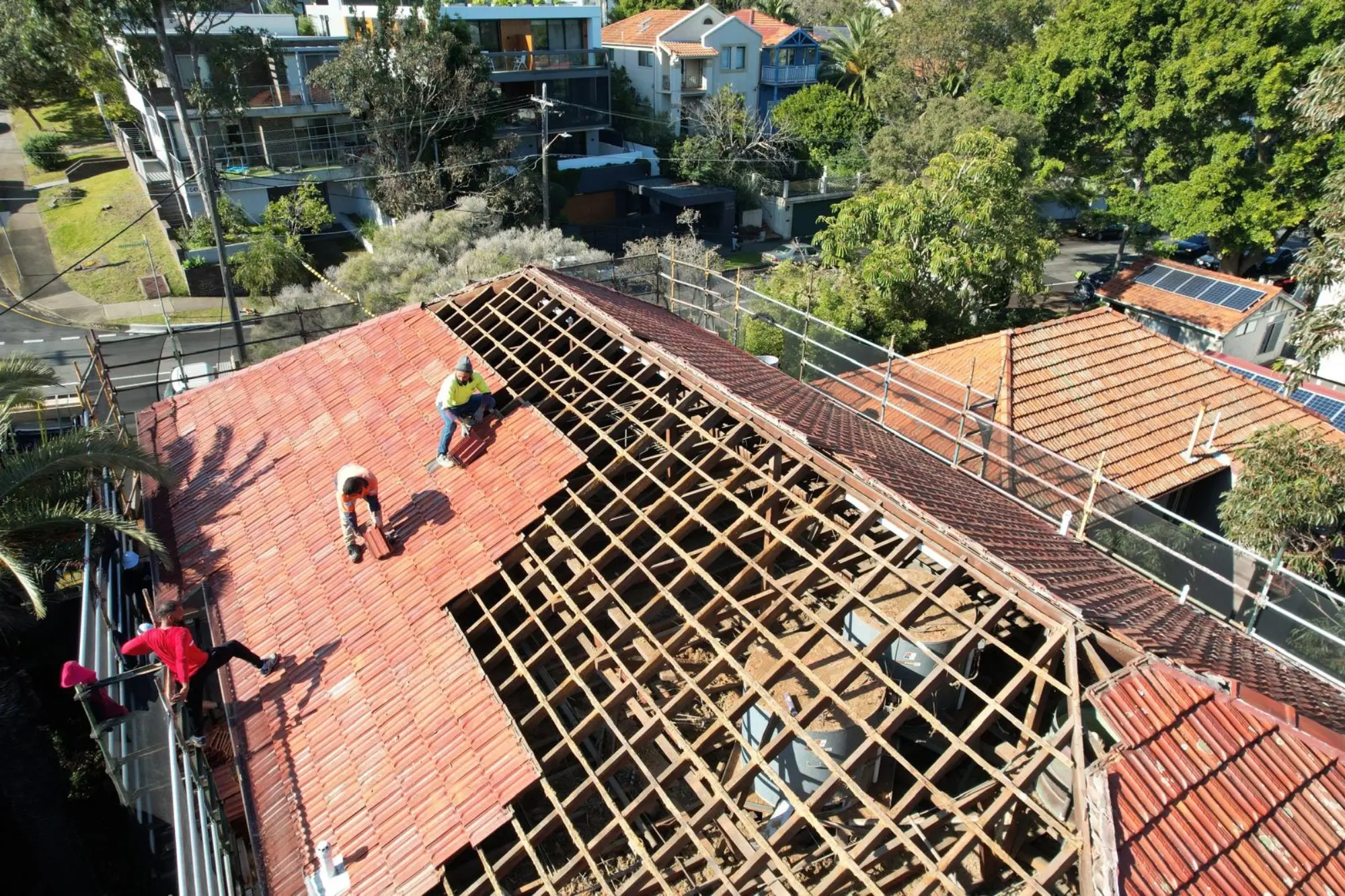 Roofers replacing terracotta roof tiles on a Sydney home with the timber battens exposed
